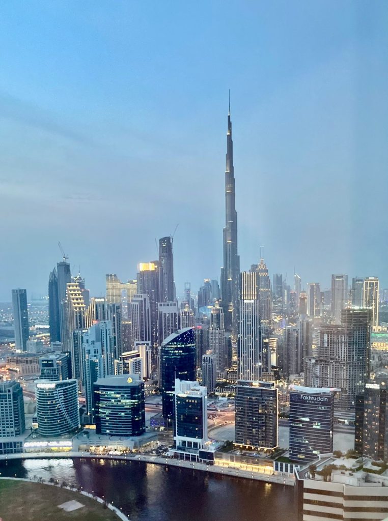 Vista panorâmica do Burj Khalifa em Dubai, o edifício mais alto do mundo, iluminado ao entardecer com o skyline moderno dos Emirados Árabes Unidos ao fundo.