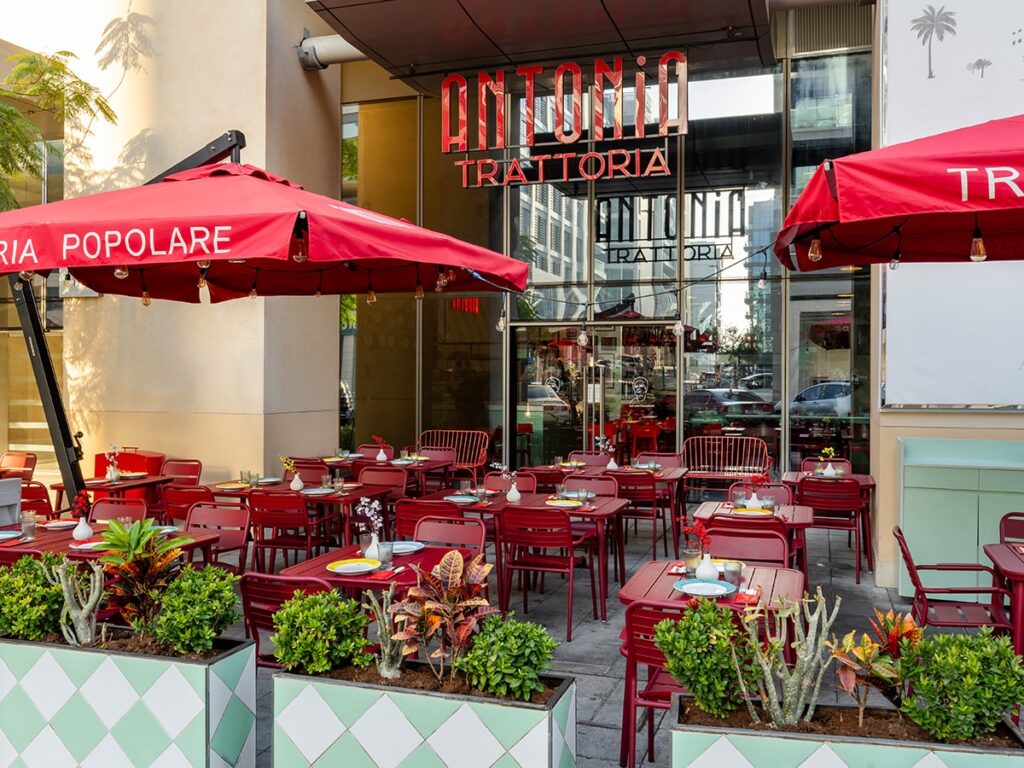 Foto panorâmica de um restaurante italiano luxuoso em Dubai, com salão elegante, mesas brancas impecavelmente montadas, iluminação suave, serviço refinado e ambiente exclusivo no coração financeiro da cidade. Atmosfera clássica, sofisticada e premium, ideal para turismo de luxo, jantares especiais e encontros de negócios nos Emirados Árabes Unidos.