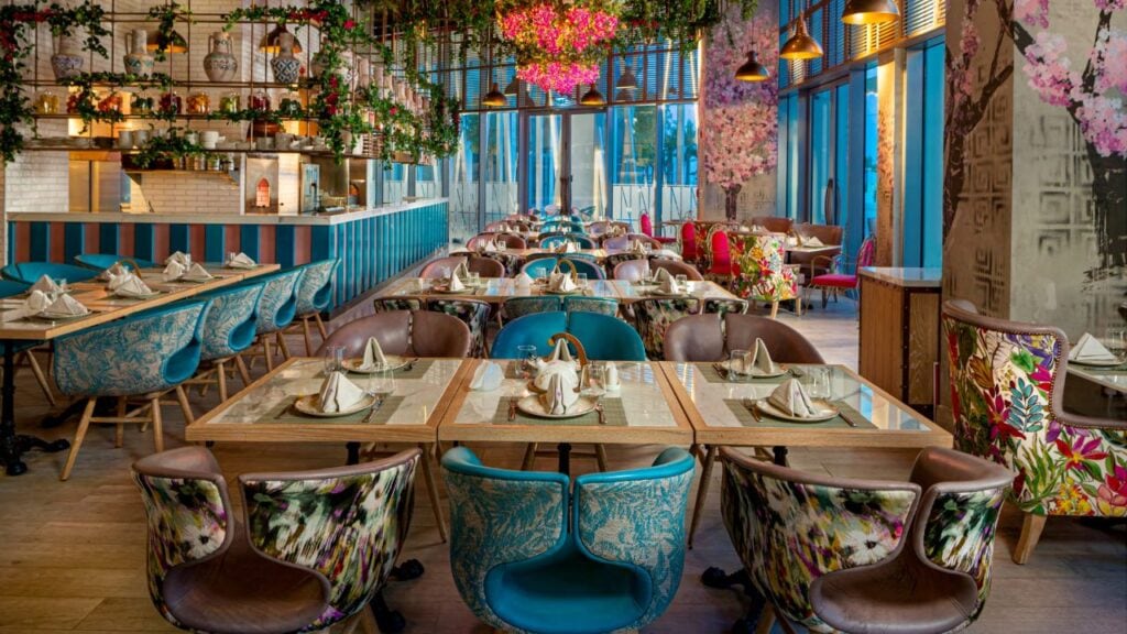Foto panorâmica de um restaurante italiano luxuoso em Dubai, com salão elegante, mesas brancas impecavelmente montadas, iluminação suave, serviço refinado e ambiente exclusivo no coração financeiro da cidade. Atmosfera clássica, sofisticada e premium, ideal para turismo de luxo, jantares especiais e encontros de negócios nos Emirados Árabes Unidos.
