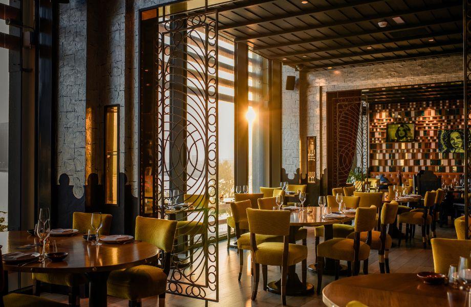 Foto panorâmica de um restaurante italiano luxuoso em Dubai, com salão elegante, mesas brancas impecavelmente montadas, iluminação suave, serviço refinado e ambiente exclusivo no coração financeiro da cidade. Atmosfera clássica, sofisticada e premium, ideal para turismo de luxo, jantares especiais e encontros de negócios nos Emirados Árabes Unidos.