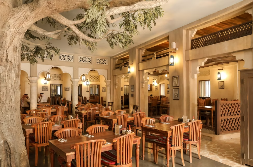 Foto panorâmica de um restaurante italiano luxuoso em Dubai, com salão elegante, mesas brancas impecavelmente montadas, iluminação suave, serviço refinado e ambiente exclusivo no coração financeiro da cidade. Atmosfera clássica, sofisticada e premium, ideal para turismo de luxo, jantares especiais e encontros de negócios nos Emirados Árabes Unidos.