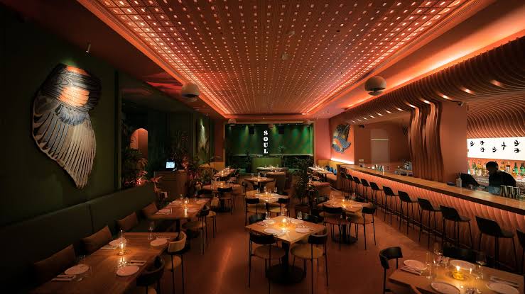 Foto panorâmica de restaurante moderno em Dubai com design artístico, iluminação sofisticada, ambiente elegante, pratos contemporâneos, apresentações musicais ao vivo e atmosfera vibrante. Experiência gastronômica sofisticada em Business Bay.