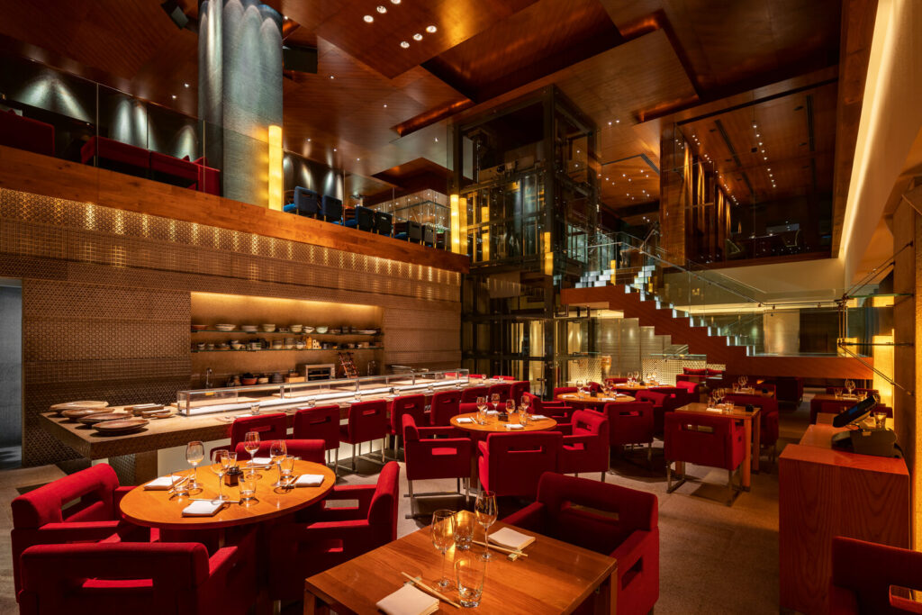 Foto panorâmica de um restaurante italiano luxuoso em Dubai, com salão elegante, mesas brancas impecavelmente montadas, iluminação suave, serviço refinado e ambiente exclusivo no coração financeiro da cidade. Atmosfera clássica, sofisticada e premium, ideal para turismo de luxo, jantares especiais e encontros de negócios nos Emirados Árabes Unidos.
