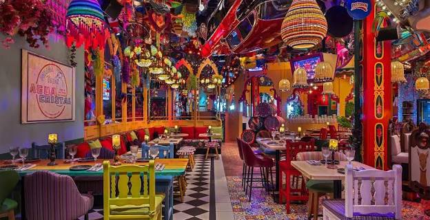 Foto panorâmica de um restaurante luxuoso em Dubai, com vista para o skyline moderno da cidade ao fundo. Ambiente sofisticado com mesas elegantes, decoração refinada e atmosfera exclusiva que transmite uma experiência gastronômica premium e turismo de luxo nos Emirados Árabes Unidos.