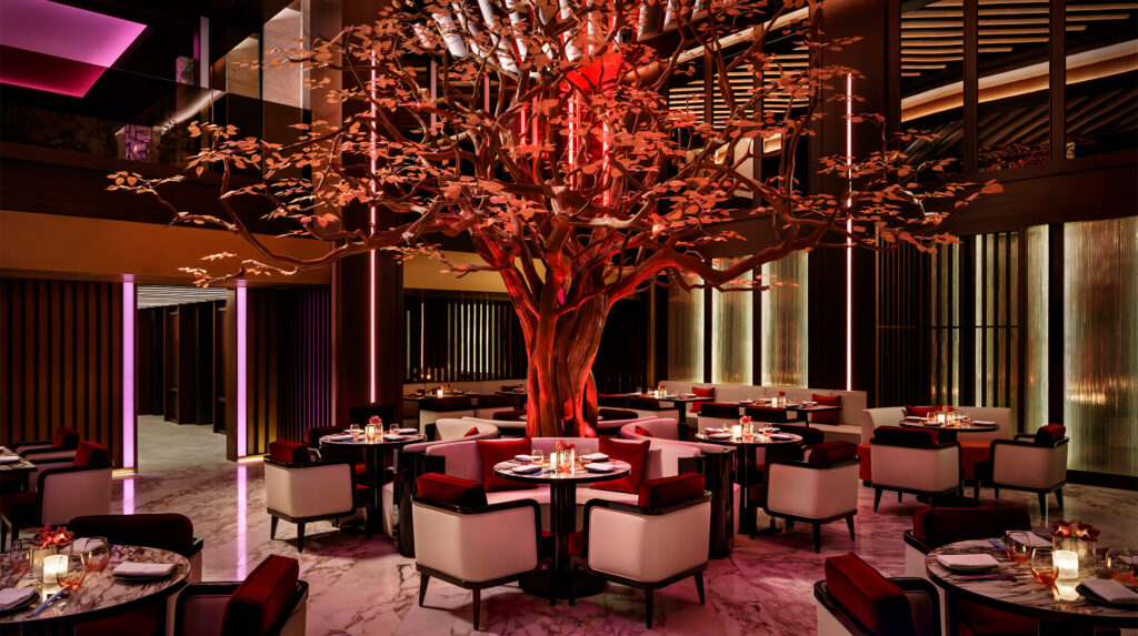 Foto panorâmica de um restaurante luxuoso em Dubai, com vista para o skyline moderno da cidade ao fundo. Ambiente sofisticado com mesas elegantes, decoração refinada e atmosfera exclusiva que transmite uma experiência gastronômica premium e turismo de luxo nos Emirados Árabes Unidos.