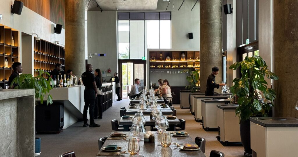 Foto panorâmica de um restaurante italiano luxuoso em Dubai, com salão elegante, mesas brancas impecavelmente montadas, iluminação suave, serviço refinado e ambiente exclusivo no coração financeiro da cidade. Atmosfera clássica, sofisticada e premium, ideal para turismo de luxo, jantares especiais e encontros de negócios nos Emirados Árabes Unidos.