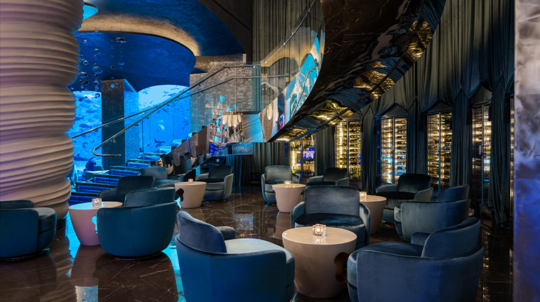 Foto panorâmica de um restaurante luxuoso em Dubai, com vista para o skyline moderno da cidade ao fundo. Ambiente sofisticado com mesas elegantes, decoração refinada e atmosfera exclusiva que transmite uma experiência gastronômica premium e turismo de luxo nos Emirados Árabes Unidos.