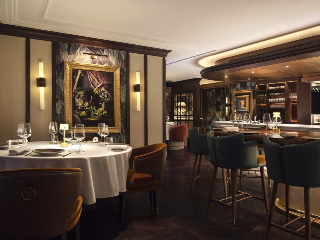 Foto panorâmica de um restaurante luxuoso em Dubai, com vista para o skyline moderno da cidade ao fundo. Ambiente sofisticado com mesas elegantes, decoração refinada e atmosfera exclusiva que transmite uma experiência gastronômica premium e turismo de luxo nos Emirados Árabes Unidos.